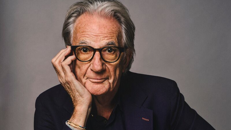 Paul Smith sitting with his head in his hand against a grey background.