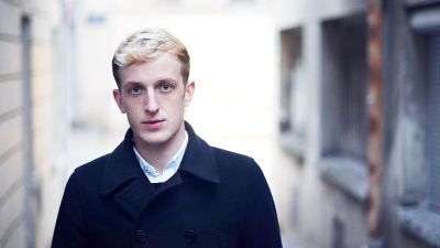 Edouard Louis wearing a black coat standing on a street.