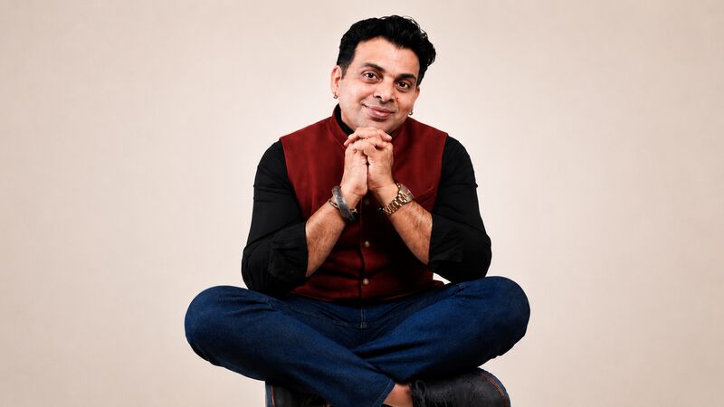 Amit Tandon sitting cross-legged wearing a red shirt