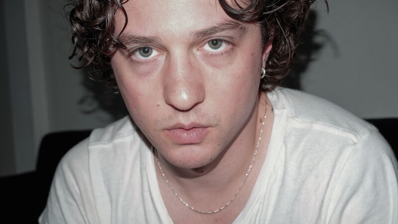 A man in a white t-shirt looking directly at the camera