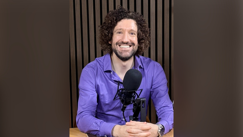 Presenter Greg Jenner smiling with a microphone
