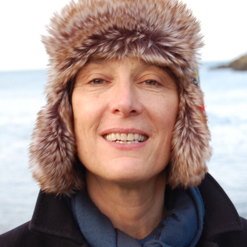 Cornelia Parker smiling directly into the camera wearing a fluffy hat at the beach