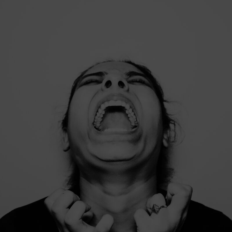 Black and white photo of woman screaming, her mouth is open and her hands are slightly clenched.
