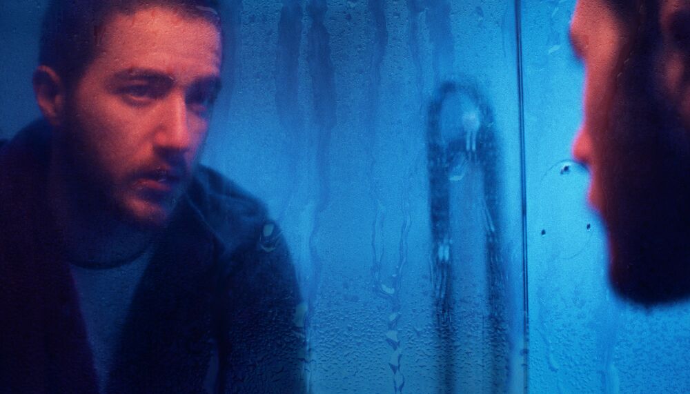 Man stares into a mirror with water dripping down it.