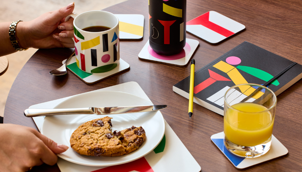 Table with Block Scene products including a mug with coffee, orange juice and a chocolate chip cookie