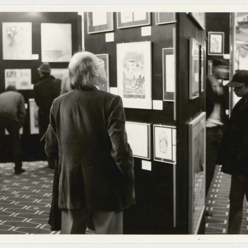 People looking at sketches on a wall in the archive exhibition