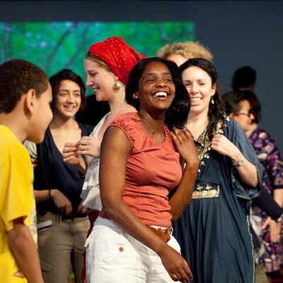 Group of people of different ages in a room smiling and interacting with each other