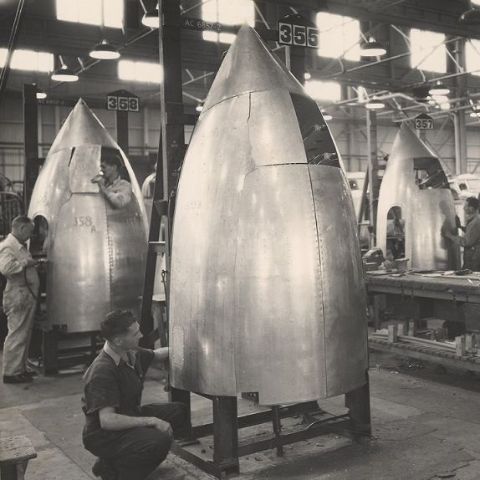 Black and white image men building missiles