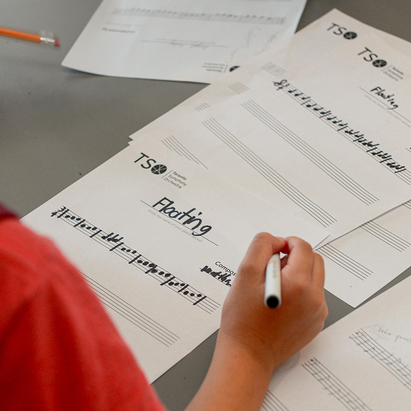 Child writing music at a station at the Open House