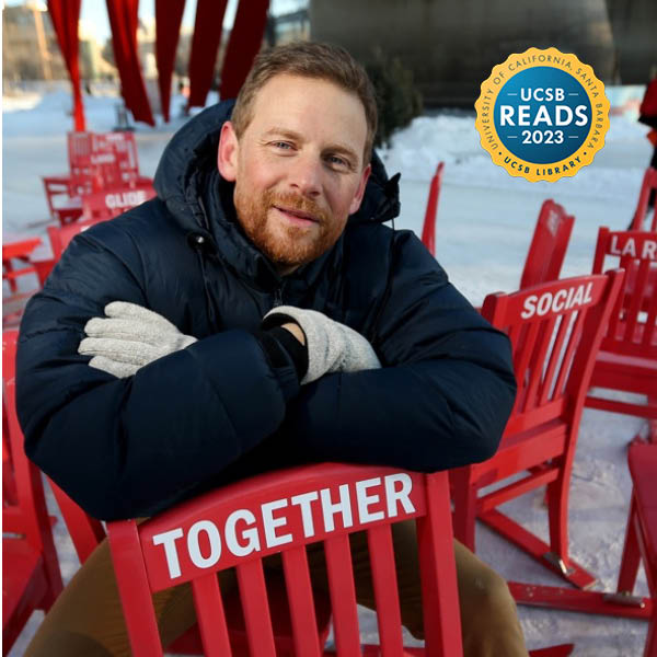 Charles Montgomery in a blue jacket, leaning on a chair with the word "Together" printed on it.