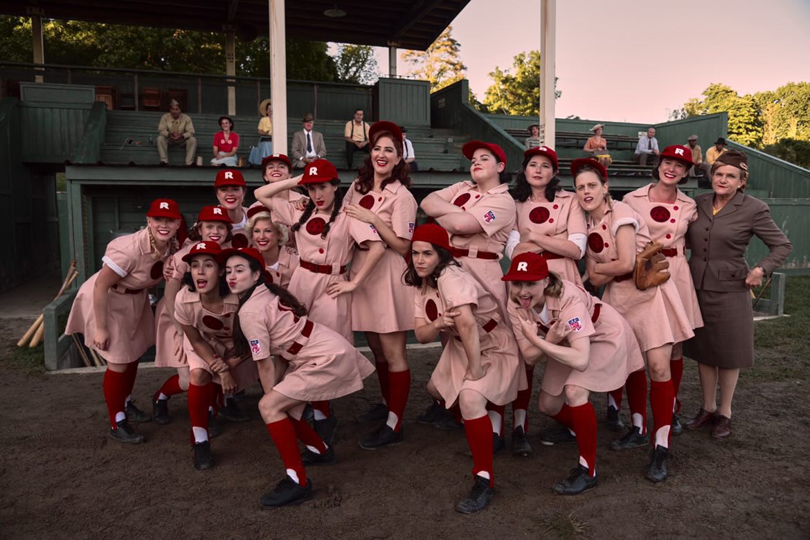 A photo of Melanie Field ’16 (arms crossed, standing center) and the cast of A League of Their Own.