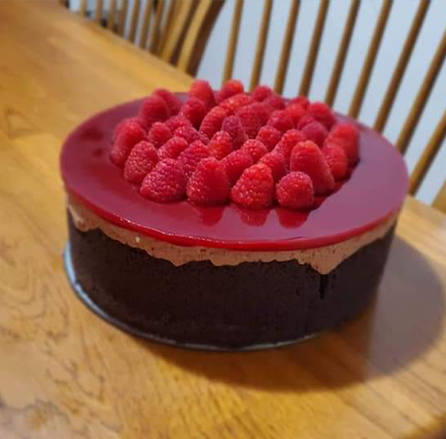 photo, a chocolate cake topped decoratively with raspberry mouse and fresh berries