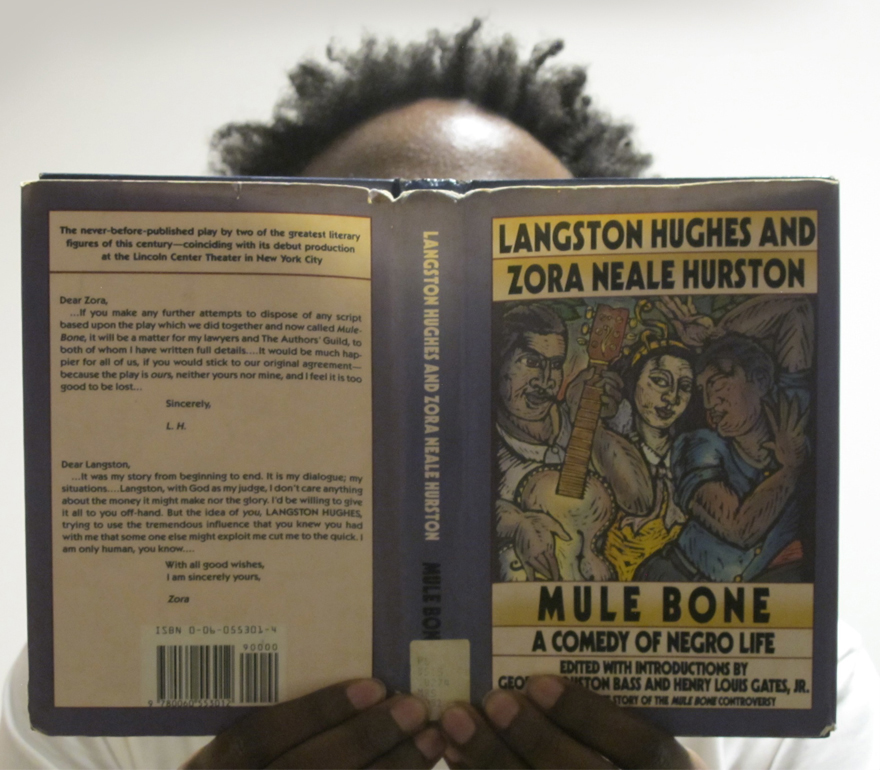 a man with his face hidden by the book MULE BONE: A Comedy of Negro Life by Langston Hughes and Zora Neale Hurston